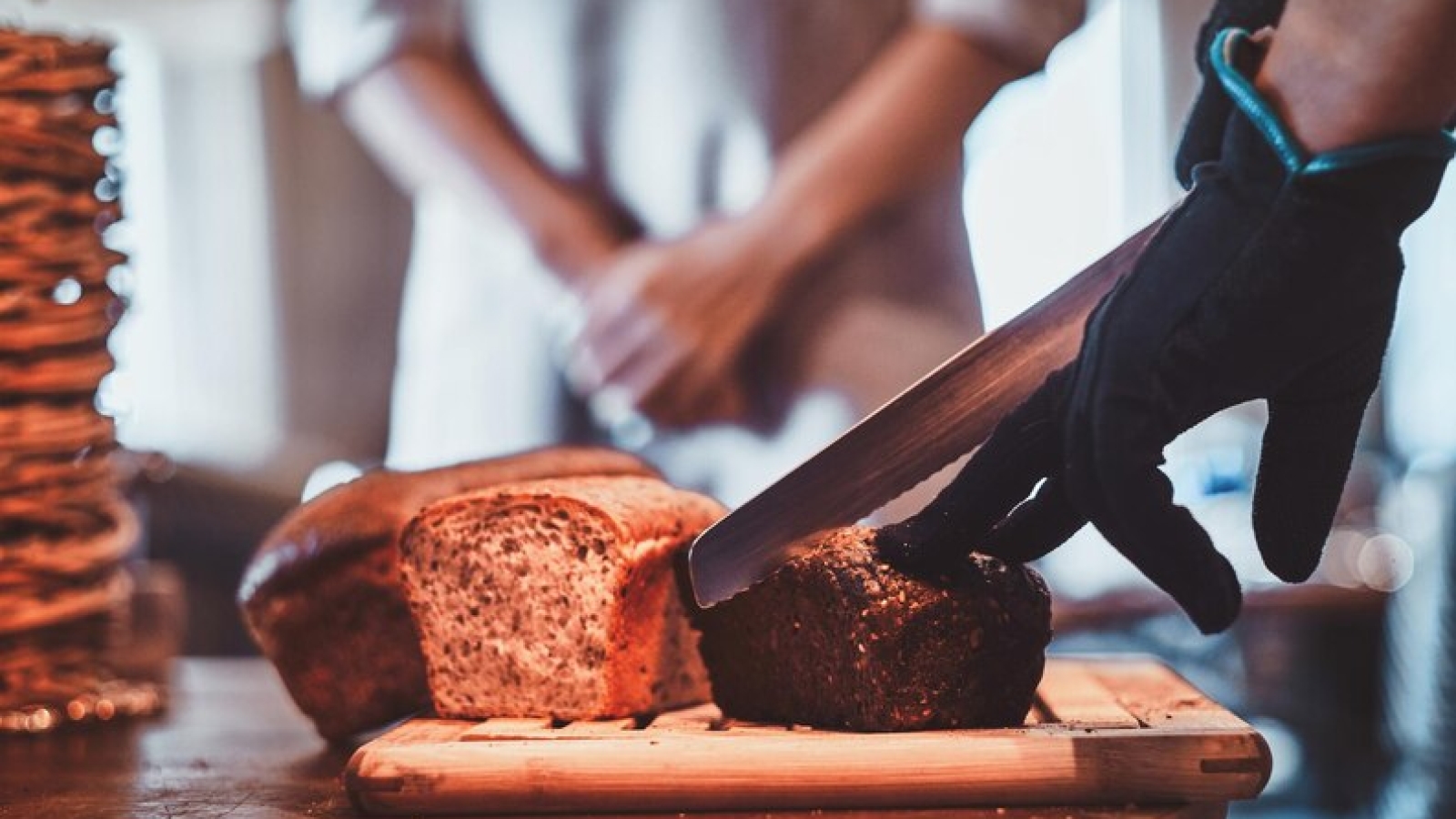 [freepicdownloader.com]-man-gloves-is-slicing-tasty-loaf-lunch-small-artisan-caffeteria-medium